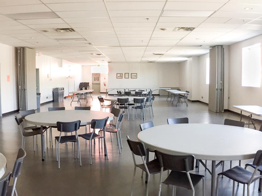 Spacious empty room with round tables and chairs.