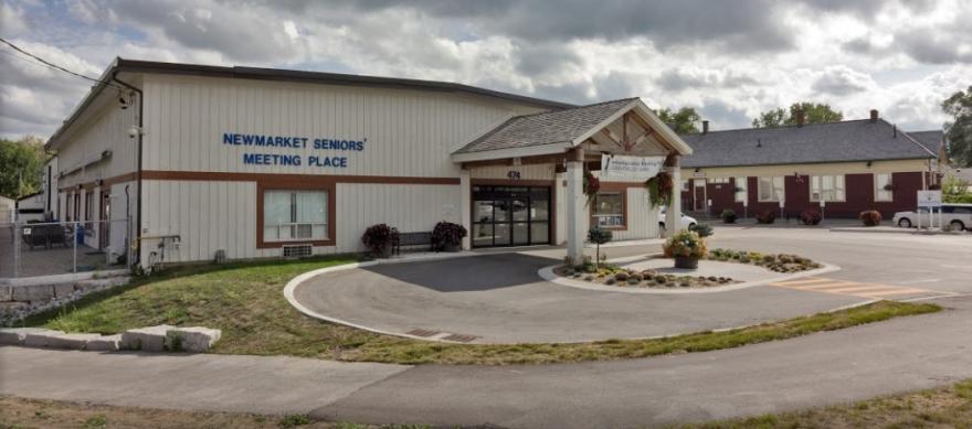 Community center with a parking lot, cloudy sky.