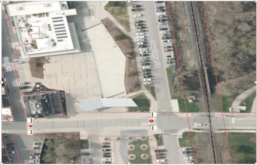 Aerial view of a parking lot near a railway and a building.